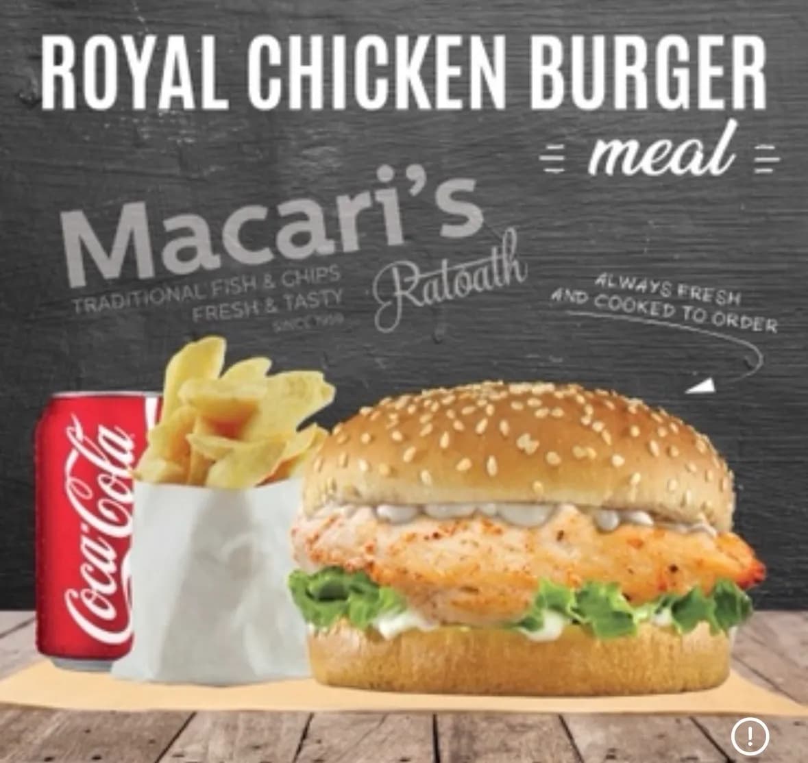 Royal chicken burger meal with chips and a can of Coca-Cola, served on a wooden table with a dark chalkboard-style background.